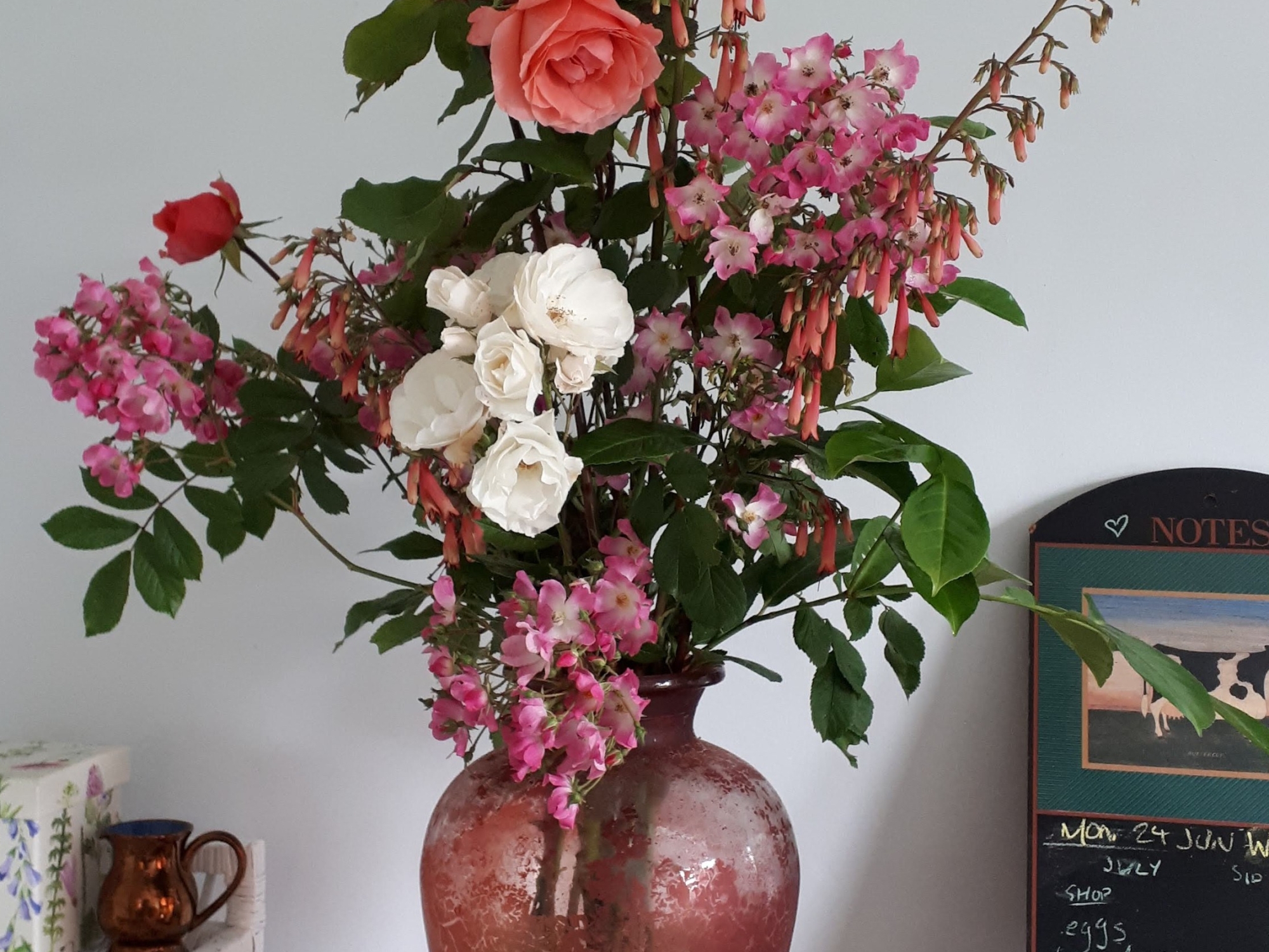 Roses, penstemon, and laurel in a big red vase